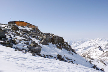 Fototapeta na wymiar winter mountain landscape in the Monte Rosa range in Switzerland with the Mantova mountain hut on ist rocky promontory