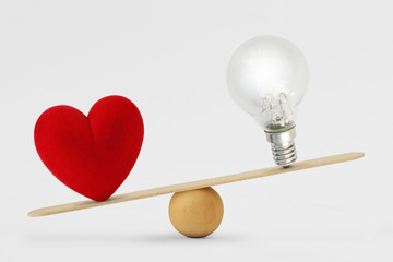 Heart and light bulb on scale - Concept of love priority over brain in life