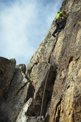 The climber climbs up the rock wall.