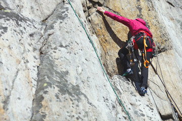 A girl climber climbs the rock wall. Climbing gear. Climbing equipment.