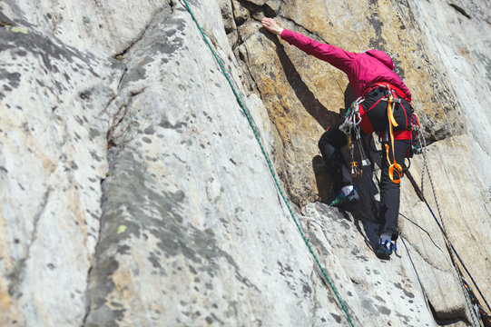 A girl climber climbs the rock wall. Climbing gear. Climbing equipment.