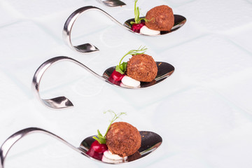 Portion spoons with snack in batter with greens