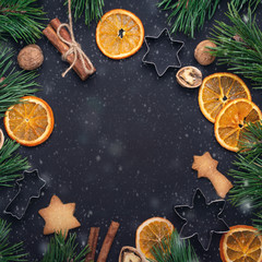 Obraz na płótnie Canvas Homemade fresh cookies Fir branches Dried slices of orange Cookie cutters Christmas concept Nuts Cinnamon Top view Copy space Snow effect