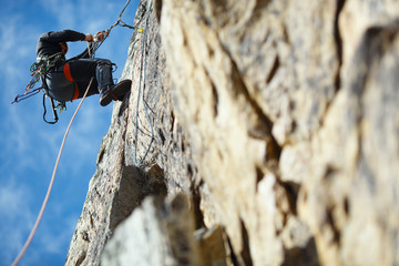 The climber is hanging on a safety rope on a rock wall.