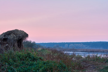 Foggy cold autumn evening in rural area.  Hut near the lake