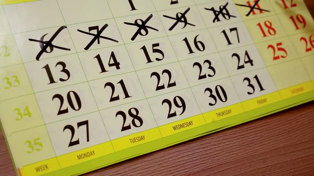 close up. woman hand marker on the calendar crosses off the past days of the week and plans activities for the remaining dates