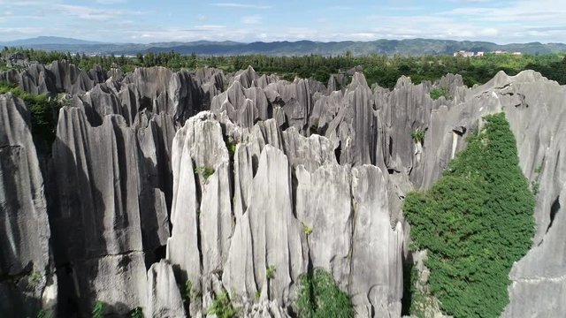 Tilting drone shot of visitors at classic pavilion building among rock formations of Shilin Stone Forest, a landmark tourist destination in Yunnan, China