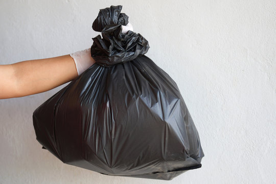 hand holding garbage black bag isolate on white background