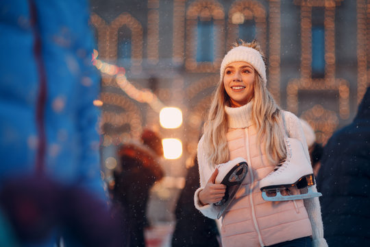 Young smiling woman with skates on the ice rink