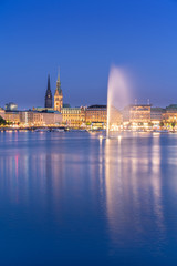 Fototapeta na wymiar The Inner Alster Lake (German: Binnenalster) in Hamburg, Germany. View of the inner city at dusk with the fountain reflecting in the water.