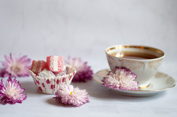 A tea cup of black tea with a piece of homemade marmalade.Home-made marmalade with chrysanthemum heads on the table.