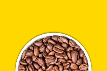 Coffee seeds in a white ceramic mug isolated on empty copy space yellow background. 