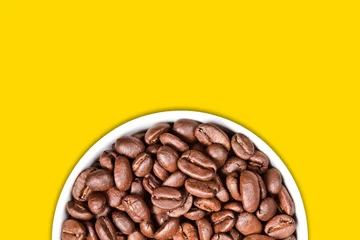 Foto auf Acrylglas Coffee seeds in a white ceramic mug isolated on empty copy space yellow background.  © Paweł Michałowski