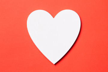 White wooden heart shape isolated on red background.