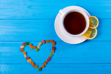 Green tea with heart shape over blue background. top view with teacup
