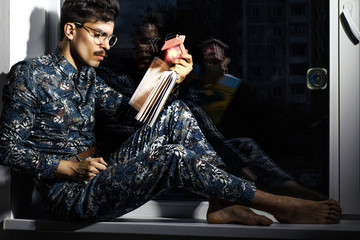 Pyatigorsk, Russia. 10/31/2017 A handsome guy sits at night by the window and reads a book.