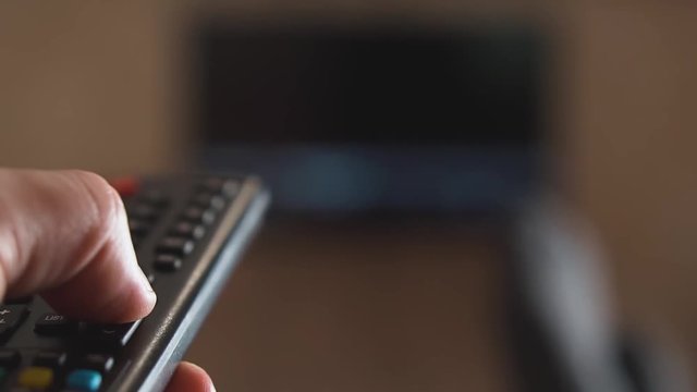 Male hand holding Tv remote control and program switching.