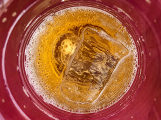 close up on fresh beer with cool ice on red plastice cup.