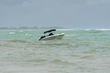 Anchored boat in rough water during tropical storm at the beach of Grand Baie in mauritius.