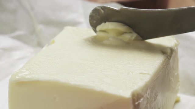 Slow motion of female teen hands scraping butter with a knife