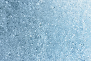 Fototapeta na wymiar Frozen winter window pane coated shiny icy patterns. Frost background, closeup. Extreme north low temperature. Natural ice glass