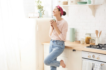 Young woman drinking a morning coffee in kitchen
