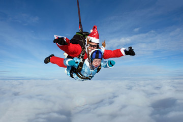 Christmas skydiving. Santa Claus and little girl are in the sky.