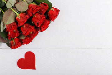 Red roses and hearts on a white wooden table. Concept of Women's Day or St. Valentine. Copy space.