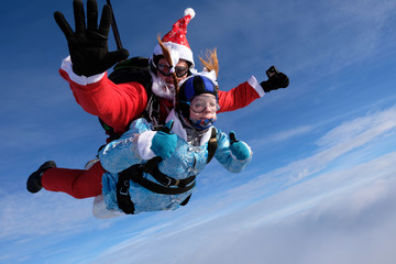 Christmas skydiving. Santa Claus and little girl are in the sky.