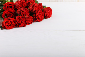 Red roses bouquet on a white wooden table. Concept of Women's Day or St. Valentine. Copy space.