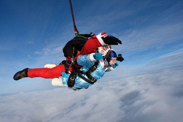 Christmas skydiving. Santa Claus and little girl are in the sky.