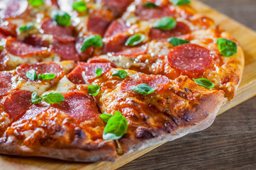 Pepperoni Pizza with Mozzarella cheese, salami, Tomatoes, pepper, Spices and Fresh Basil. Italian pizza on wooden table background