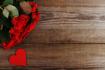 Red roses and hearts on wooden table. Concept of Women's Day or St. Valentine. Copy space.