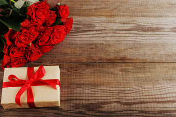 A bouquet of red roses, a gift on wooden table. Concept of Women's Day or St. Valentine. Copy space.
