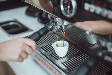 Professional espresso machine pouring fresh coffee into white ceramic cup
