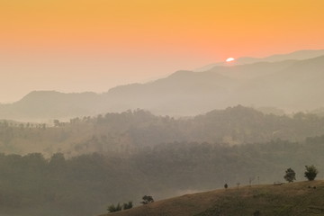 Mountain view misty morning of many hills around with soft mist with colorful sun light in the sky background, sunrise at Doi Mae Salong, Chiang Rai, Thailand.