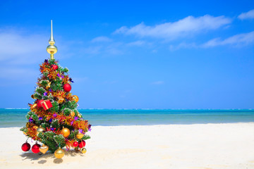 Christmas tree on the beach with blue sky, white sand and blue ocean in the background