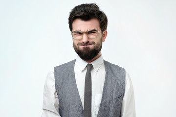 Funny young man grimacing, inflating cheeks, holding his breath. It is smelling bad in room.