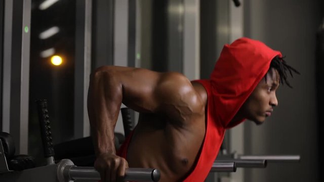 African american man push ups in gym on parallel bars