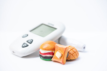 Junk food toy model  and blood glucose meter. Bad nutrition,health care and medical.