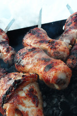 Fried Chicken Legs On The Grill with crispy crust. Closeup duck drumsticks on skewers roasted over charcoal
