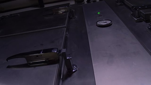 A HAND CLOSES THE DOOR ON A MORGUE COLD STORAGE UNIT.  IN 4K, 10 BIT.  ECU SLIDER SHOT.