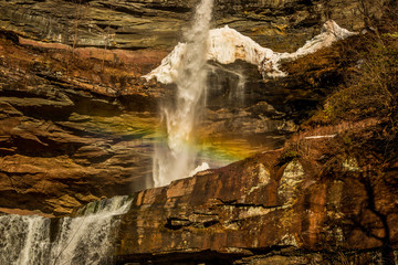 Kaaterskill Falls in the Catskill Mountains in New York on a Spring day with a rainbow running across the mist of the waterfall.