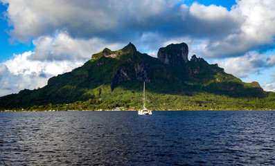 Lonely catamaran anchored about near Bora-Bora island in the Leeward group of the Society Islands...