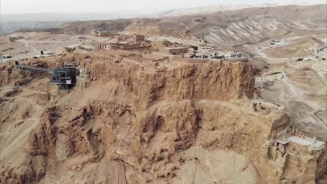 Masada - Aerial footage of the ancient fortification in the Southern District of Israel. Moving forward. Flying around Masada. The view from the top. Tourists walk among the ruins. 4k