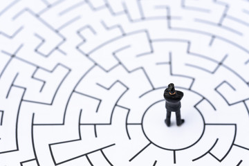 Miniature people, businessman in the labyrinth or maze figuring out the way out. Business concept,...