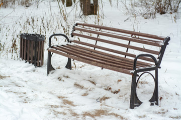 Wooden park bench covered with snow