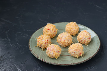 Cheese crab balls in cheese shavings located on a dark background