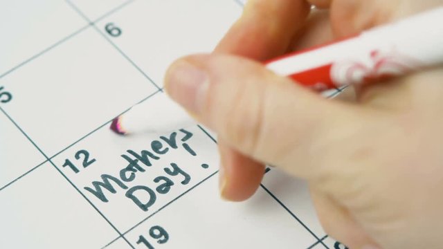 Write with a pink marker on the calendar to Mother's Day holiday. Close up 4k footage.