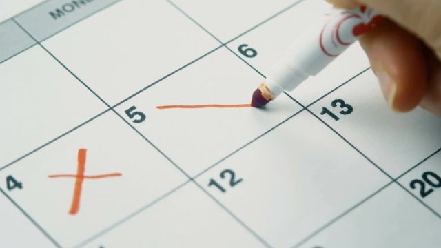 Write in calendar with red marker. Close up 4k footage.